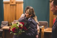 zdjęcie kolorowe przedstawia uroczystość pożegnania odchodzącego komendanta - sala sesyjna komendant przyjmuje kwiaty od policjantki