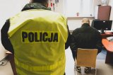 policjant przy zatrzymanym w pomieszczeniu przesłuchań