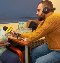 dziennikarz z mikrofonem rozmawia z kobietą której widać tylko nogi