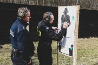 zdjęcie przedstawia zajęcia strzeleckie policjantów - policjant i instruktor przy tarczy odczytują wyniki