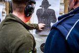 zdjęcie przedstawia zajęcia strzeleckie policjantów - policjant i instruktor przy tarczy