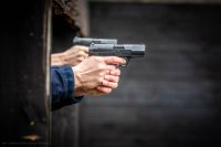zdjęcie przedstawia zajęcia strzeleckie policjantów - ręce z pistoletami zza belki ochronnej