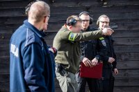 zdjęcie przedstawia zajęcia strzeleckie policjantów - instruktor tłumaczy jak zgrywać przyrządy celownicze
