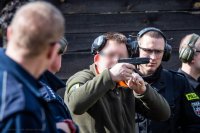 zdjęcie przedstawia zajęcia strzeleckie policjantów - instruktor tłumaczy zasadę szybkiego strzelania