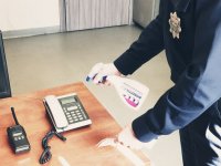 zdjęcie - policjant dezynfekuje biurko i telefon