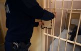policjant zamyka kratę w pomieszczeniu dla zatrzymanych