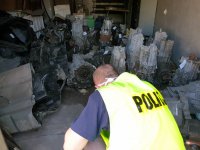 policjant sprawdzający numery zabezpieczonych części samochodowych