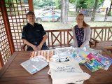 policjant i kobieta siedzący, przed nimi stół z materiałami profilaktycznymi