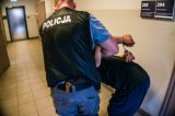 zdjęcie poglądowe - policjant prowadzi zatrzymanego