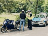 zdjęcie przedstawia policjantów w trakcie działań - kontrola dokumentów motocyklisty