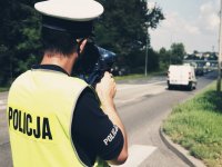 zdjęcie przedstawia policjantów w trakcie działań - policjant dokonujący pomiaru prędkości