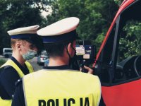 zdjęcie przedstawia policjantów w trakcie działań - policjanci pokazują kierowcy samochodu dostawczego zmierzoną prędkość na wyświetlaczu radarowego miernika prędkości