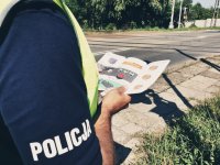 zdjęcie przedstawia działania policjantów - policjant na tle przejazdu kolejowego, w rękach trzyma ulotkę akcji
