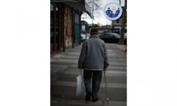 widok starszej osoby podpierającej się laską, która idzie ulicą