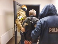 Policjanci kryminalni prowadzą zatrzymanego
