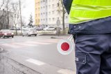 zdjęcie - policjant stojący przed przejściem dla pieszych w tle jadące samochody