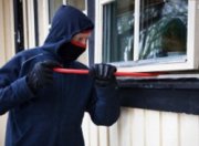 zamaskowany mężczyzna wyłamuje okno - zdjęcie poglądowe