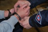 zdjęcie poglądowe, policjant zakłada kajdanki na ręce mężczyzny