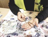 zarekwirowane wyroby jubilerskie, a policjant pokazuje złoty łańcuszek