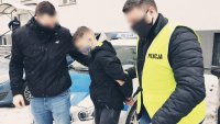 policjanci prowadzą zatrzymanego oszusta