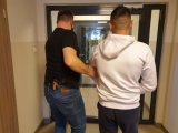 policjant prowadzi zatrzymanego