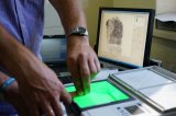 zdjęcie poglądowe - technik wykonuje odciski palców zatrzymanego