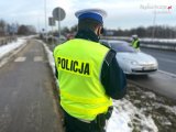 policjant z drogówki, w tle droga i samochód - zdjęcie poglądowe