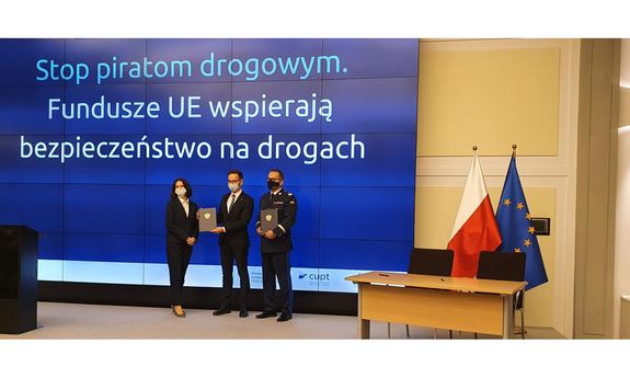 na zdjęciu trzy osoby w czasie spotkania - kobieta i dwóch mężczyzn, jeden w mundurze policyjnym