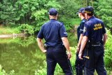 policjanci i strażnik miejski na brzegu stawu