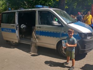 Wizerunek dziecka na tle radiowozu prezentującego poradnik &quot;Bezpieczna woda&quot;.