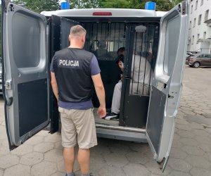 Widok zatrzymanego rozbojarza w radiowozie.