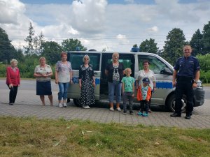 Grupa seniorów pozujących do zdjęcia na tle radiowozu