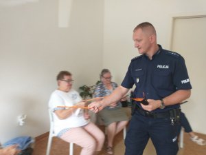 Policjant przekazujący odblaski seniorom