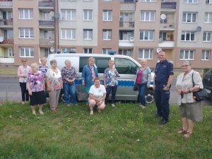 Seniorzy pozujący do zdjęcia na tle radiowozu