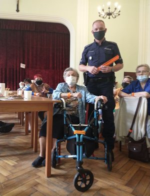 Policjant prezentujący odblaski w obecności seniorki
