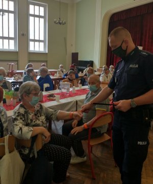 Policjant wręczający odblaski grupie seniorów