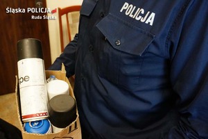 policjant trzyma pudełko z farbami w sprayu - zdjęcie poglądowe