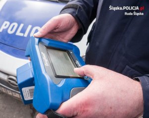 policjant trzyma w rękach urządzenie do badania na zawartość narkotyków