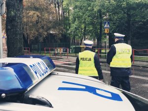 policjanci przy szkole, w tle radiowóz, zebra i znaki