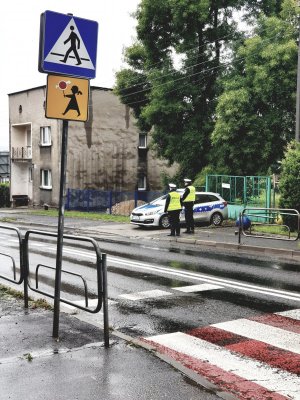 policjanci przy szkole, w tle radiowóz, zebra i znaki