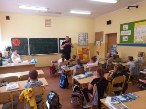 policjant w klasie z dziećmi, prowadzi pogadankę