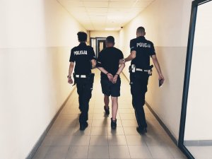 policjanci prowadzą zatrzymanego kierowcę