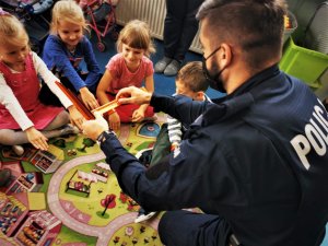policjant zakłada dzieciom odblaskowe opaski