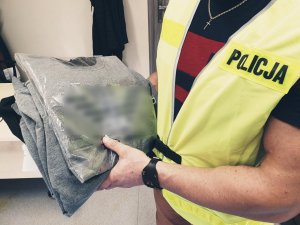 policjant trzyma przejęte podróbki odzieży