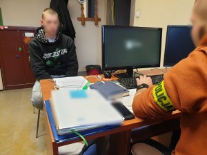 pomieszczenie biurowe, policjant rozmawia z nieletnim sprawcą