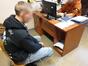 pomieszczenie biurowe, policjant rozmawia z nieletnim sprawcą