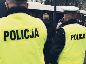 policjanci kontrolują obowiązek zakrywania ust i nosa w autobusach - na zdjęciu policjanci tyłem w tle ludzie wsiadający do autobusu