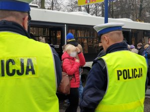 policjanci kontrolują obowiązek zakrywania ust i nosa w autobusach - na zdjęciu policjanci i osoby wysiadające z autobusu