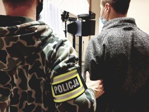 policjant i zatrzymany pedofil w pomieszczeniu do daktyloskopii i identyfikacji