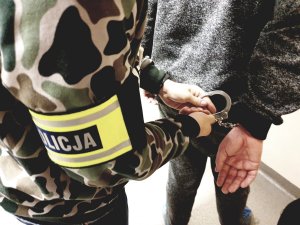 policjant zakłada kajdanki na ręce zatrzymanego pedofila